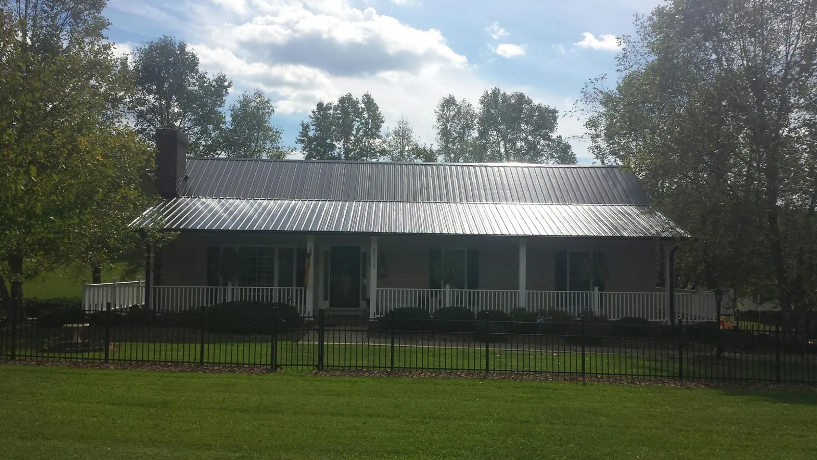 Gray metal roof on a brick ranch with a full width front porch — Gutter Guard Installation work by our crew in Cassville