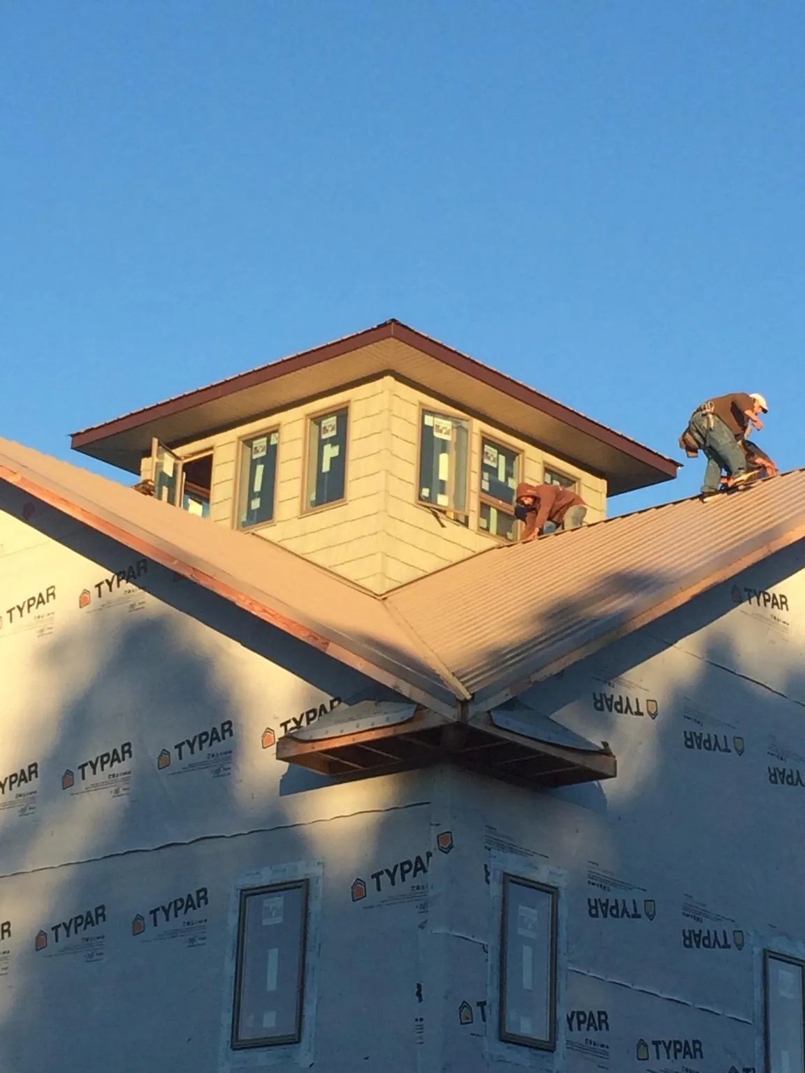 Roofers working around a rooftop cupola on a new metal roof at sunset — Roof Waterproofing in Cassville by Roofing Brothers
